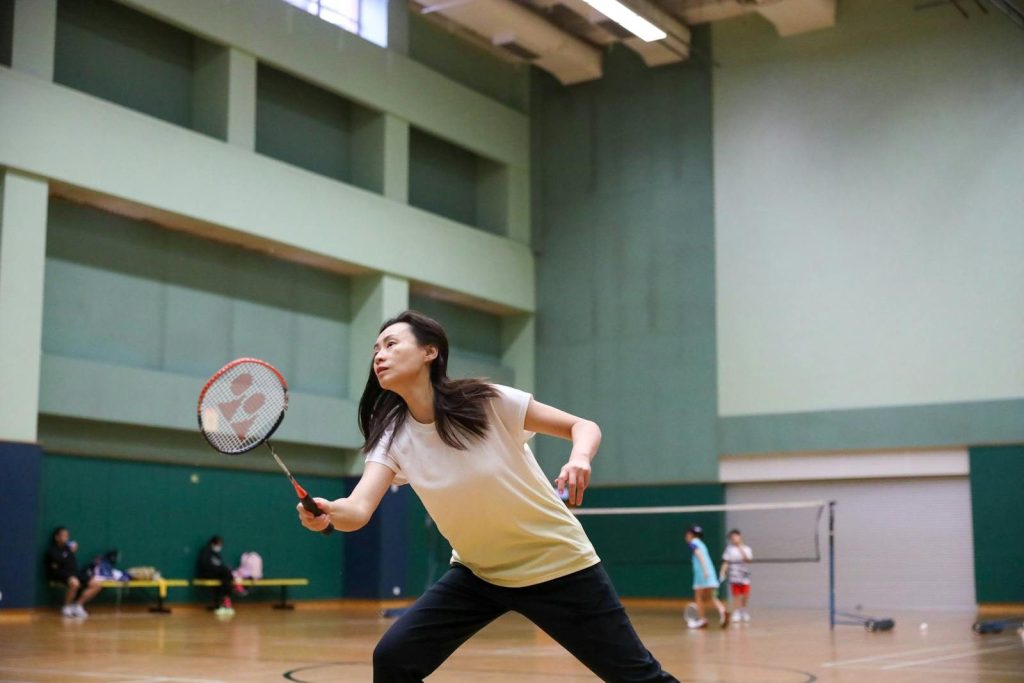 A female athlete playing badminton indoors, focused intently on the game.