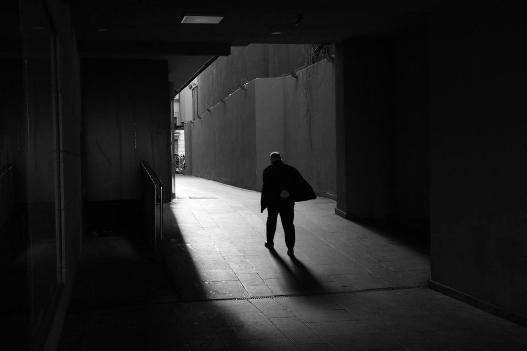 Silhouetted man walks through dark alley in Istanbul, creating a dramatic shadow effect.