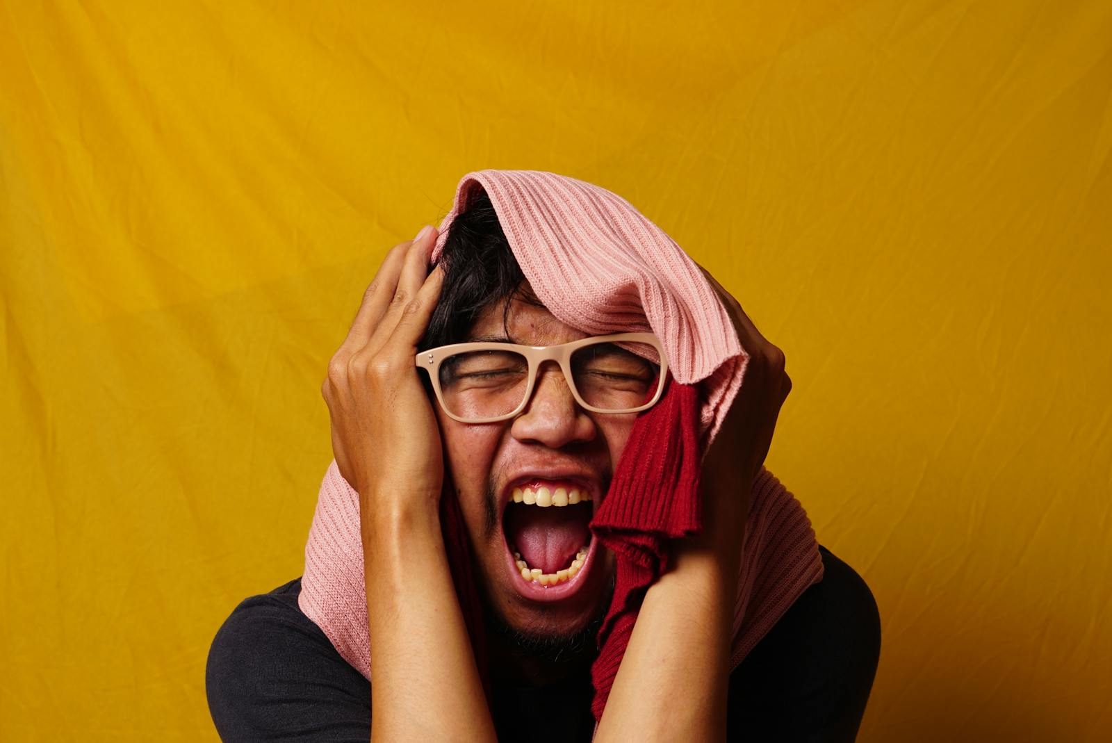 man humorously reacts with colorful clothing on a vibrant yellow background.
