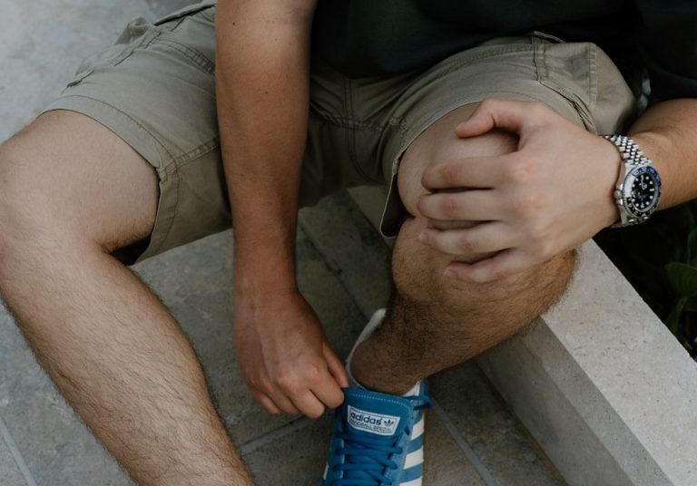 A man sitting on a ledge tying his shoes