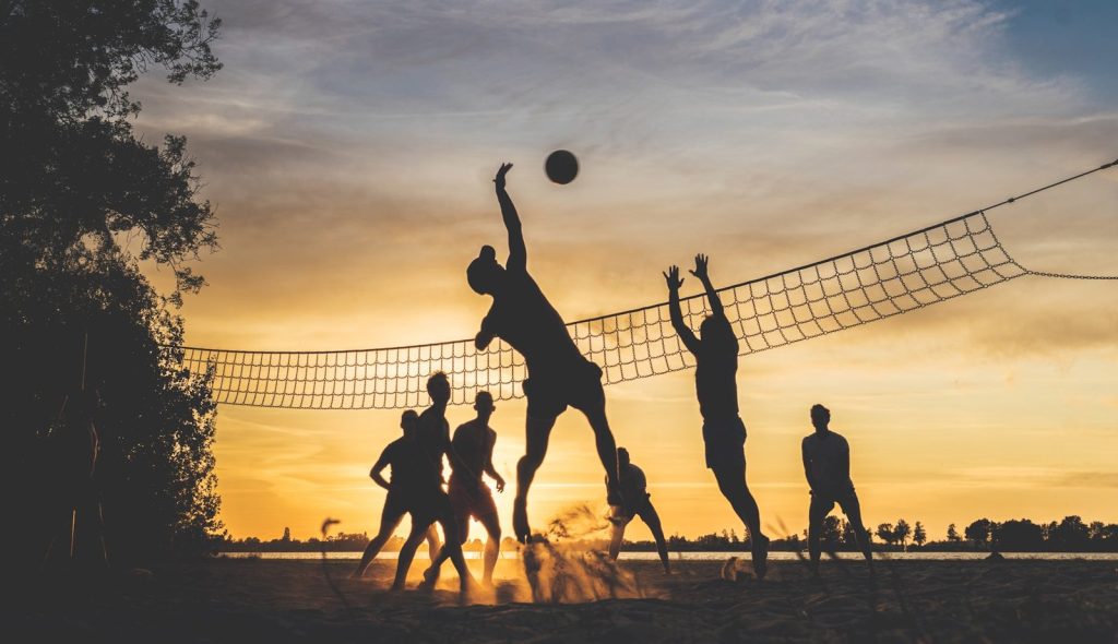 silhouettes playing beach volleyball at sunset