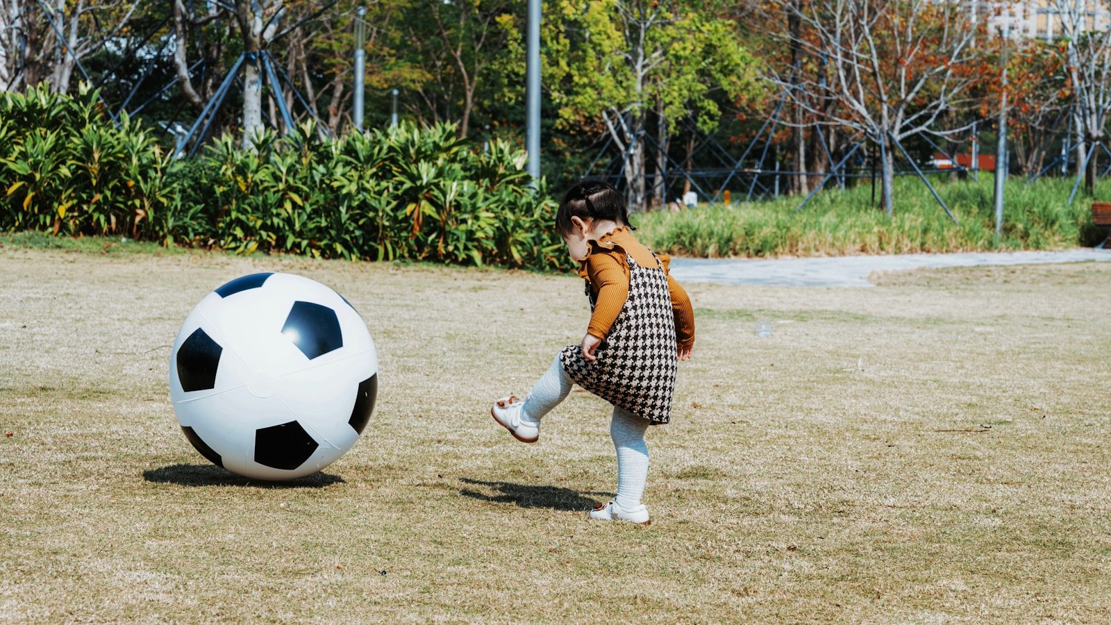 Young girl kicks a giant soccer ball in a park