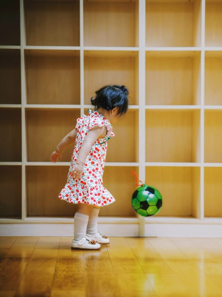 A young child plays with a green soccer ball